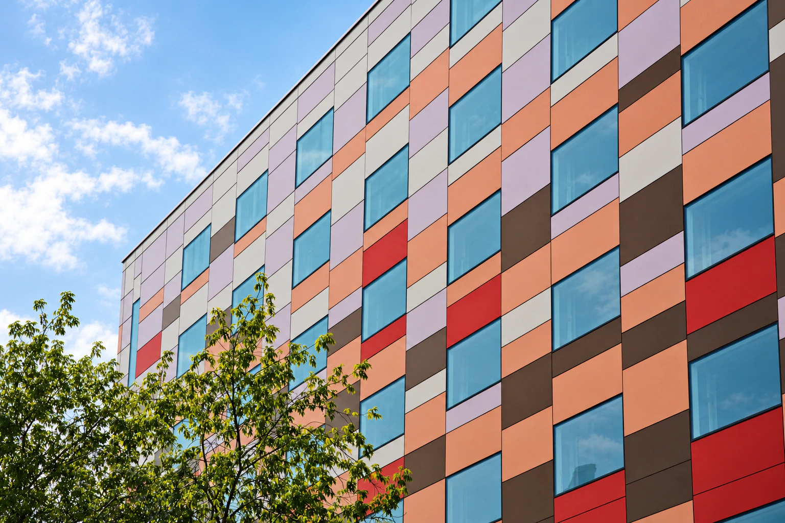 Integrated façade with coloured panels and glazing beneath a blue sky